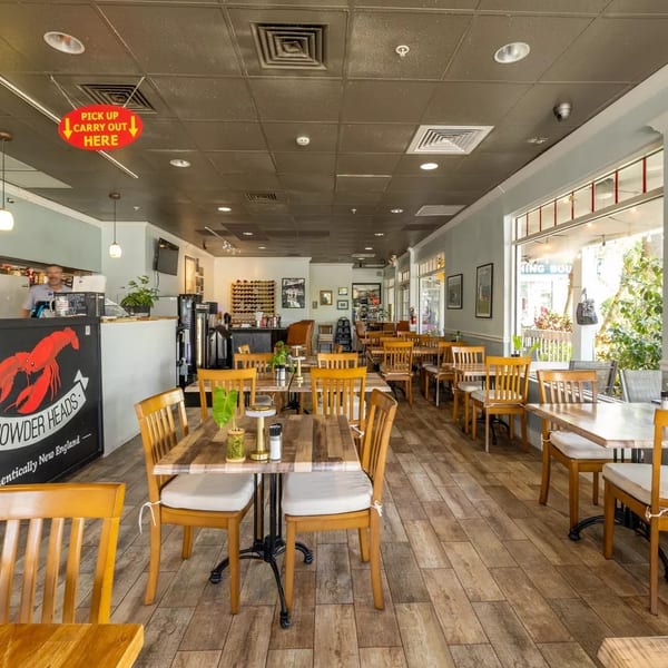 Interior of Chowder Heads restaurant with wooden tables and chairs, a counter, and large windows.