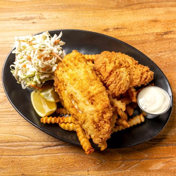 Crispy fried fish and chicken tenders with crinkle-cut fries, coleslaw, lemon, and dipping sauce.